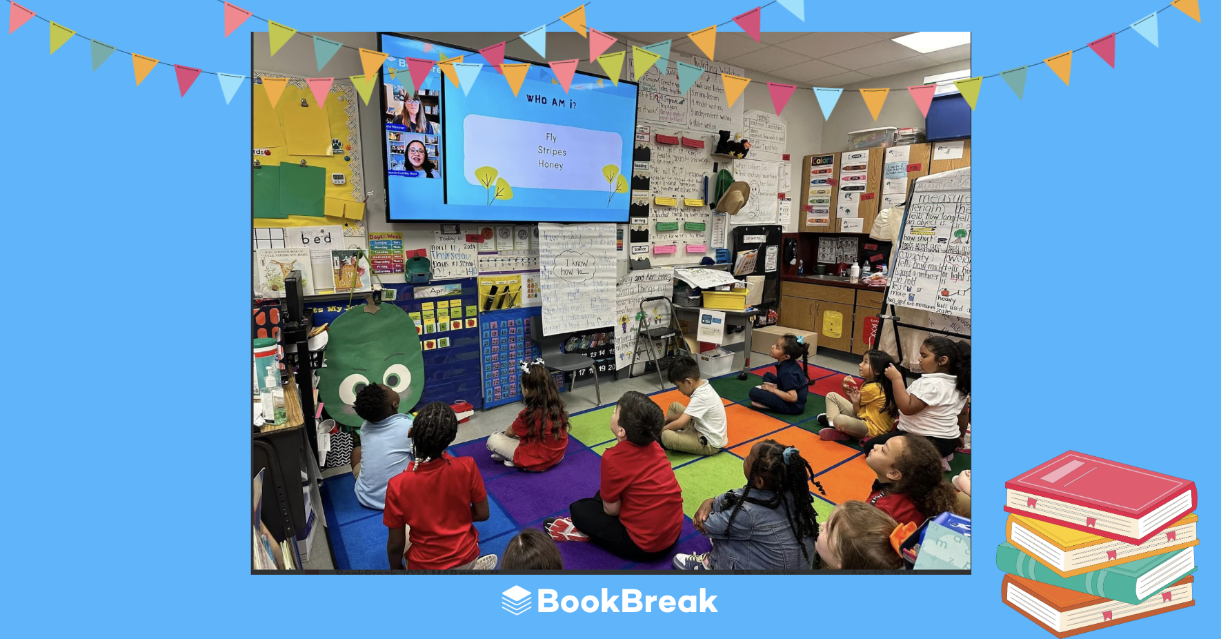 Elementary students sit on a classroom rug, highly engaged while watching a live virtual author talk on a large screen.